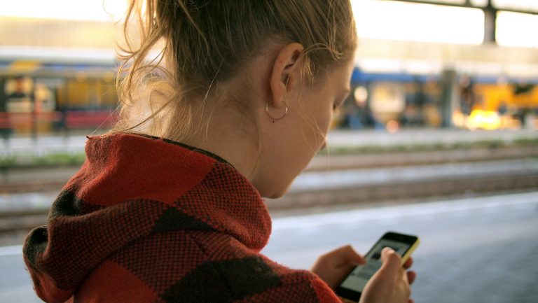 Vanaf wanneer wordt smartphonegebruik problematisch? 5 tips om verslaving tegen te gaan Vrouw kijkt op smartphone op station Leiden. Smartphoneverslaving