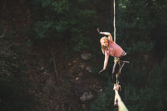 A woman is walking along a stretched sling over a forest. Waarden