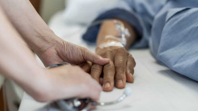 Elderly senior aged patient on bed with geriatric doctor holding hands for trust and nursing health care, medical treatment, caregiver and in-patient ward healthcare in hospital